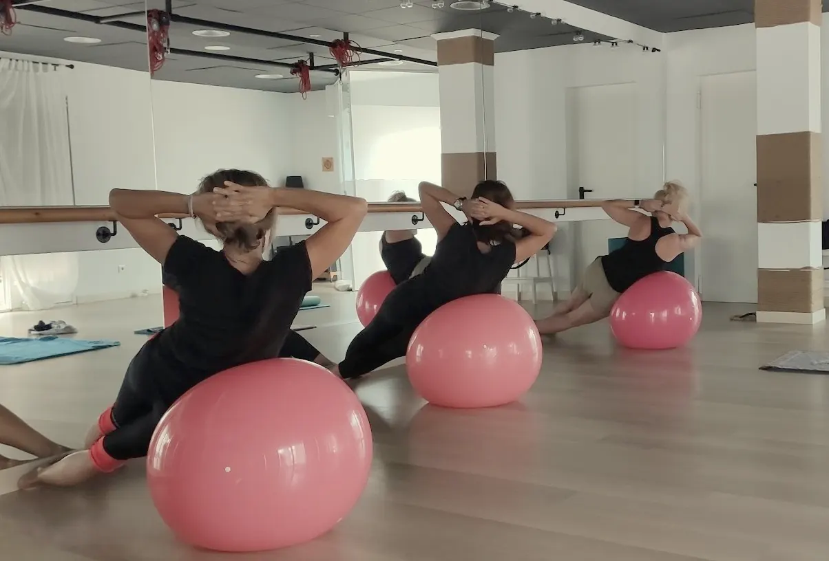 Alumnes fent Pilates Mat amb pilota davant del mirall