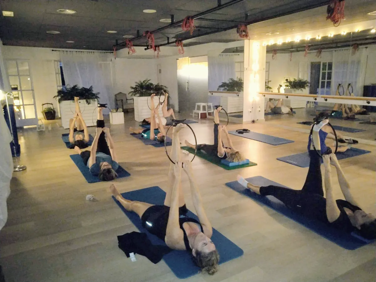 Classe de Pilates Mat amb aros, les alumnes estirades sobre les estores